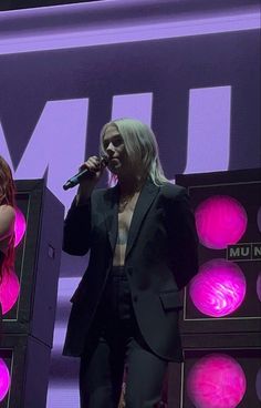 two women standing on stage with microphones in their hands