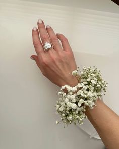 a woman's hand with a ring on it and flowers in front of her