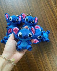 there is a hand holding three small crocheted stitched elephants in blue and pink