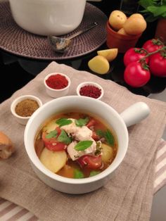 a white bowl filled with soup next to bowls of vegetables and bread on top of a table