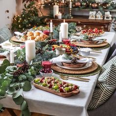 a table set for christmas dinner with candles and food