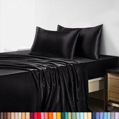 a bed with black sheets and pillows on it