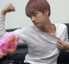 a young man sitting on top of a couch holding a pink toy in his hand