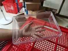 a person's hand in a plastic container on top of a red carton