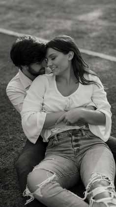 a man and woman sitting next to each other on the ground in black and white