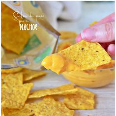 someone dipping cheese into a bowl of nachos