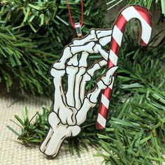 a christmas ornament with a skeleton hand holding a candy cane on it's side