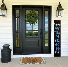 a black front door with a wreath on it and two lanterns hanging from the side