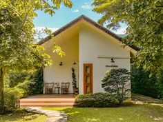 a small white house surrounded by trees and grass