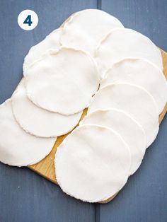 a wooden cutting board topped with lots of white pizza crusts on top of it