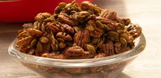 a glass bowl filled with nuts on top of a wooden table