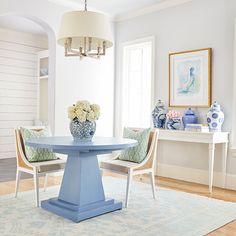 a blue and white dining room table surrounded by two chairs with flowers in vases