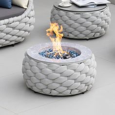 a fire pit sitting on top of a white floor next to two chairs and a table