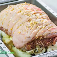 a large piece of meat sitting on top of a metal pan filled with vegetables and seasoning