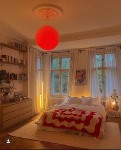 a bed room with a neatly made bed and a red light hanging from the ceiling