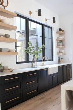 a kitchen with black cabinets and white counter tops is shown in front of a large window