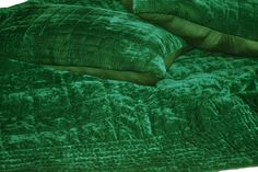 a green comforter with pillows on top of it and a pillow under the covers