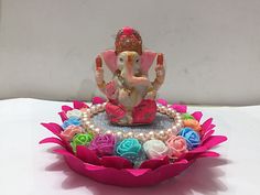 an elephant figurine sitting on top of a pink flowered bowl with pearls