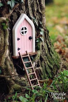 a tree with a little pink house built into it's trunk and ladder up to the door