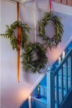 two wreaths hanging on the wall next to candles