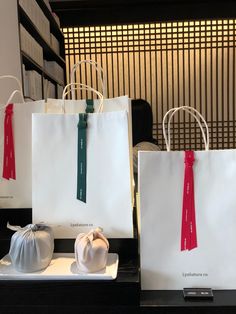 two bags with red and green ribbons on them sitting on a table next to each other