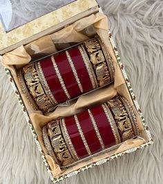 two red and gold bracelets sitting in a box on a furnishing floor