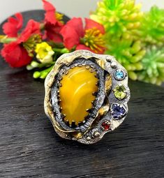 Baltic Amber Gemstone Ring in sterling silver with gold accents size 7 adjustable to bigger size Materials:  Silver 925, 24k Gold plated accents, Baltic Amber, Peridot, Garnet, Ioite, Blue Topaz Face of the ring:  Height - 35mm, Width-35mm, band - 9mm Unique Handcrafted One-of a-kind Design Ring Each Piece of Jewelry in my Collection is Absolutely One of a Kind! When you start wearing a piece of my jewelry you will fall in love with it more and more each day and feel that good Energy and Love th Unique Citrine Rings With Gemstone Accents, Unique Multi-stone Yellow Jewelry, Unique Yellow Multi-stone Jewelry, Amber Rings With Gemstone Accents For Gifts, Unique Multi-stone Citrine Rings, Artisan Jewelry With Gemstone Accents For Anniversary, Unique Gemstone Accented Rings As Gift, Yellow Gemstone Fusion Jewelry, Unique Rings With Gemstone Accents Gift