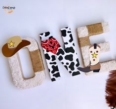 the letters are made out of wood and decorated with cow print, cowboy hats, and stars