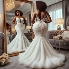 a woman in a wedding dress looking at herself in the mirror with her back to the camera