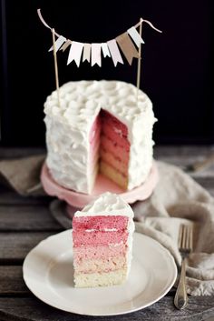 a piece of cake on a plate with a fork and bunting banner in the background