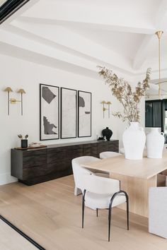 a dining room table with chairs and vases on it