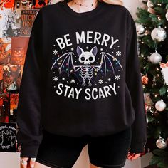 Celebrate the holidays with a quirky gothic edge! This unique sweatshirt features a skeleton bat wrapped in festive lights, bringing spooky cheer to your holiday season. Perfect for fans of dark humor and holiday fun, this cozy unisex design is great for group gatherings, holiday parties, or matching with friends and family. Stand out this season with a little skeletal charm! Available in plus sizes--grab yours today! All of our sweatshirts are custom made to order ► ITEM DETAILS: * Classic unisex crewneck sweatshirt * Ribbed knit collar with seam - Ribbed knit makes the collar highly elastic and helps retain its shape * Fabric blends: medium-heavy fabric blend of 50% cotton and 50% polyester * Fabric blends: Heather Sport colors - 60% polyester, 40% cotton * Double-needle stitching at the Goth Christmas Sweater, Christmas Goth Outfit, Goth Christmas Outfit, Emo Christmas, Gothic Holiday, Merry Creepmas, Bat Skeleton, Skeleton Christmas, Goth Christmas