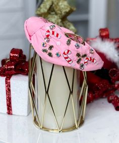 a pink hat sitting on top of a white container next to red and white presents