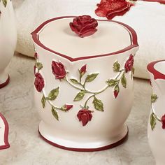 red roses on white ceramic containers with matching cups and saucers sitting on a marble surface