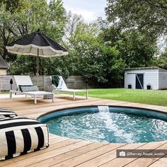 a hot tub sitting on top of a wooden deck next to lawn chairs and an umbrella