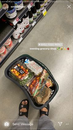 a person standing in front of a grocery cart filled with food and drinks on the floor