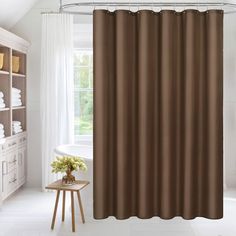 a brown shower curtain in a bathroom next to a white bath tub and window with curtains