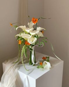 a white vase with orange and white flowers