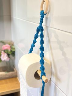 a roll of toilet paper hanging on a wall next to a blue rope wrapped around it