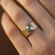 a woman's hand wearing a gold ring with a blue topazte stone