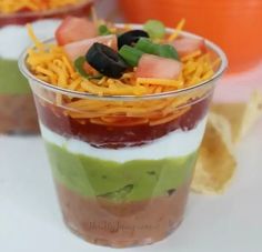 three cups filled with different types of dips and chips on top of each other