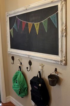 a chalkboard and coat hooks are hung on the wall next to a backpack hanging from hooks