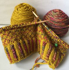 two balls of yarn are next to each other with knitting needles in the middle one is yellow