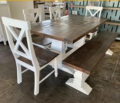 a wooden table with two white chairs next to it and a bench on the other side