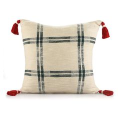 a white pillow with red tassels on the sides and a black plaid pattern