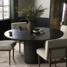 a round table with chairs around it and a vase filled with flowers on the top