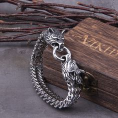 a silver bracelet sitting on top of a wooden box next to some branches and twigs