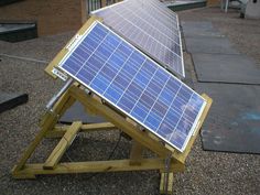 a solar panel sitting on top of a wooden stand in front of a brick building