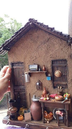 a doll house made out of clay and wood with lots of stuff on the table