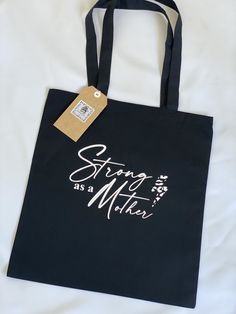 Strong as a Mother Black Tote Bag Ideal Canvas Cotton tote bag for mums, to carry shopping, books or everyday items.  Long handles for comfort.  Dimensions 36cmx40cm Large Capacity Bags For Shopping On Mother's Day, Casual Shoulder Bag For Mother's Day, Black Double Handle Shoulder Bag Gift, Letter Print Bags For Shopping On Mother's Day, Mother's Day Large Capacity Tote Shoulder Bag, Large Capacity Everyday Shoulder Bag For Mother's Day, Mother's Day Gift Shoulder Bag, Black Softback Shoulder Bag For Shopping, Rectangular Shoulder Bag For Mother's Day